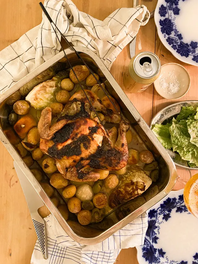 Hel kyckling i en ugnsform med rotfukter och citronsås