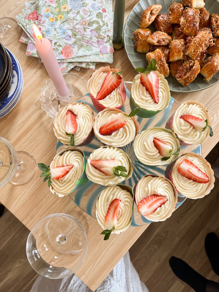 Muffins toppade med frosting och en bit av en jordgubbe